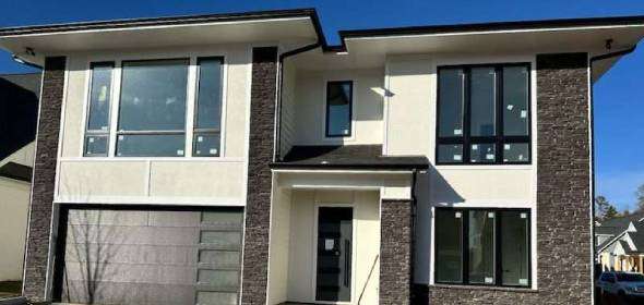 A person wearing a tool belt inspects the countertop in a partially renovated kitchen with white cabinets and black walls.